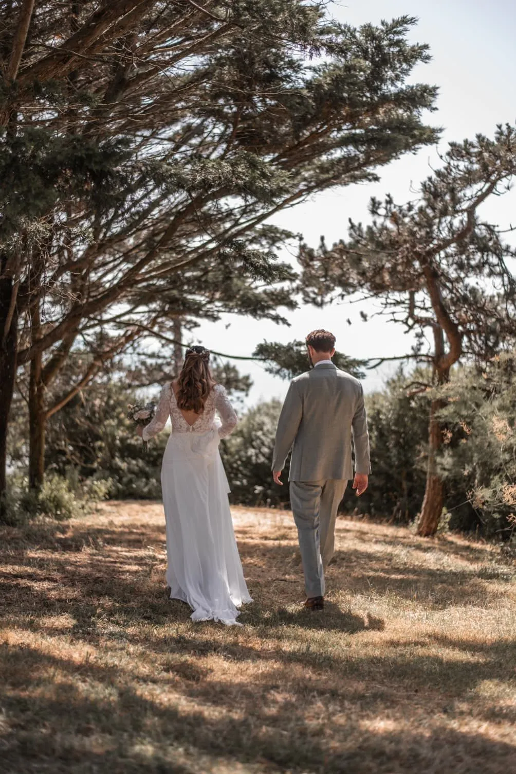Des mariés marchent sous les pins, au bord de la mer